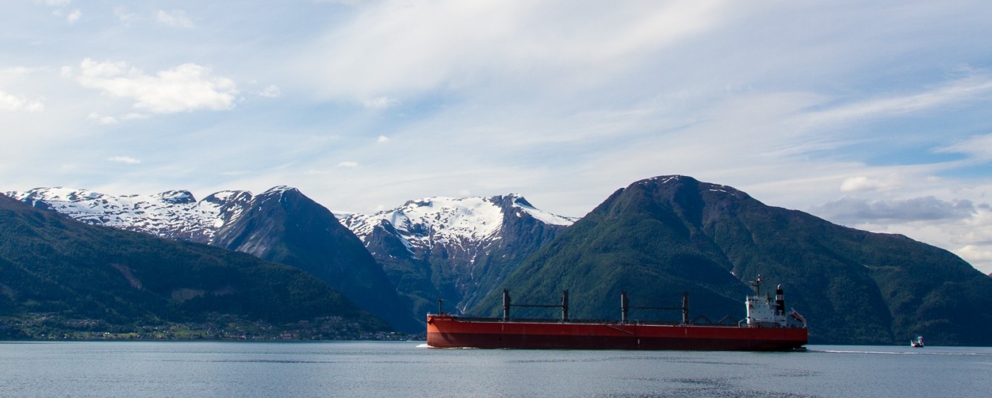 Tomt bulkskip som passerer snødekte fjell i Sognefjorden